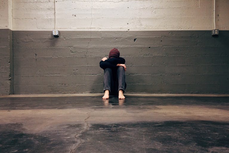 A person sitting alone in a corner, evoking themes of solitude and emotion.